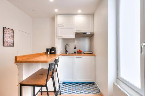 une petite cuisine avec des armoires blanches et un comptoir en bois dans l'établissement 388 Suite Trousseau - Superbe Appartement à Paris, à Paris