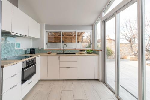 une cuisine avec des placards blancs et une grande fenêtre dans l'établissement Mon Rêve, charmant cabanon les pieds dans l'eau à la Madrague, confortable et lumineux, à Hyères