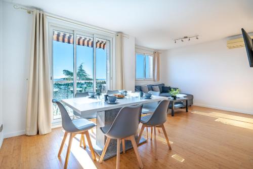 une salle à manger avec une table, des chaises et un canapé dans l'établissement Superbe 3p vue mer avec parking, à Nice