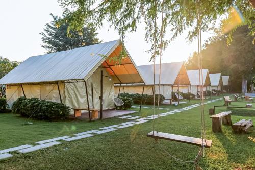 a row of tents in a park with swings at The Camp Chiangkhan in Loei