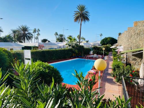 una piscina en un patio con palmeras en Puerto Rico duplex with community pool close to the beach, en Puerto Rico de Gran Canaria