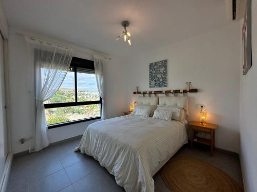 ein Schlafzimmer mit einem Bett und einem großen Fenster in der Unterkunft ViveVera - Chalet Palmera Golf Valle del Este in Vera