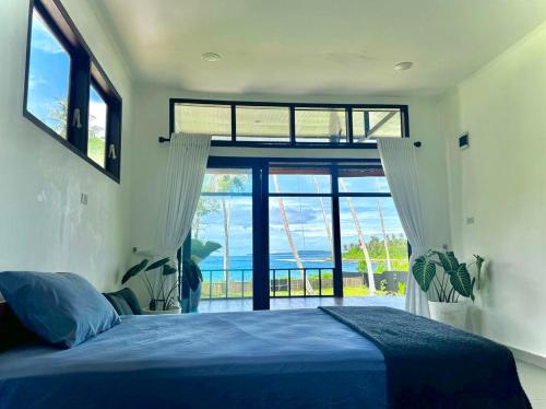 a bedroom with a blue bed and a large window at Villa Pandan Simeulue in Salul
