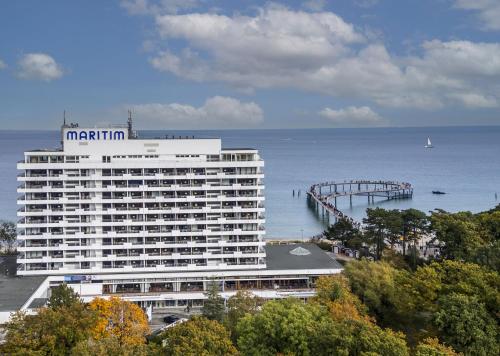 a large white building next to the ocean with a pier at Maritim Seehotel Timmendorfer Strand in Timmendorfer Strand