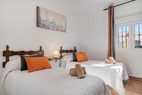 a bedroom with two beds with orange and blue pillows at Casa Pilar in Ronda