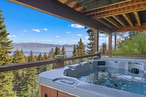 a hot tub on a deck with a view of the water at Luxury Lakeview Retreat - Hot Tub, SUP, Sauna & More! in Carnelian Bay