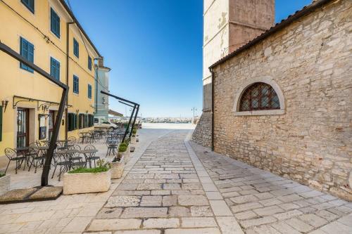 a cobblestone street next to a building with tables and chairs at Holiday Home Doda in Fažana - 100 m from the Sea in Fažana