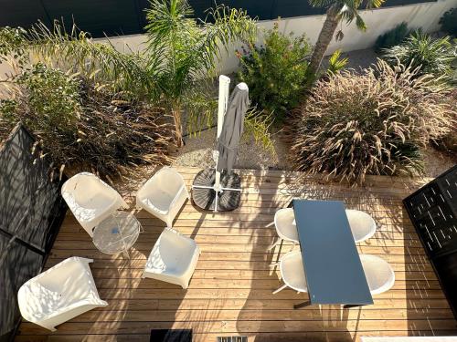 a group of white chairs and an umbrella on a deck at Les Loges de la Mer - Pérols in Pérols
