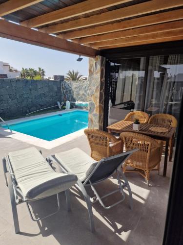 a patio with chairs and a table and a swimming pool at villa martha in Yaiza