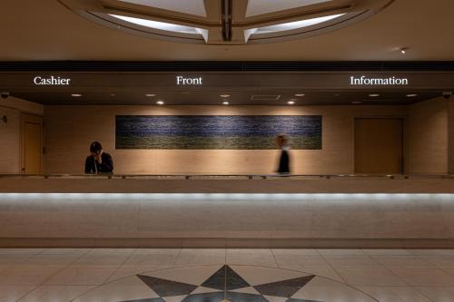 a lobby of a building with two people standing at a counter at New Sunpia Tsuruga in Tsuruga
