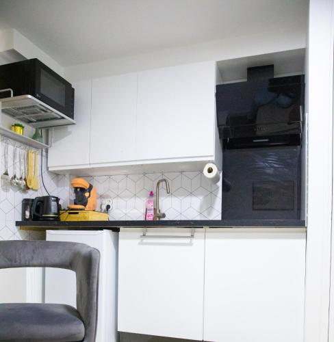 a white kitchen with white cabinets and a sink at Le Relax Place - Metro 5 Bobigny in Bobigny