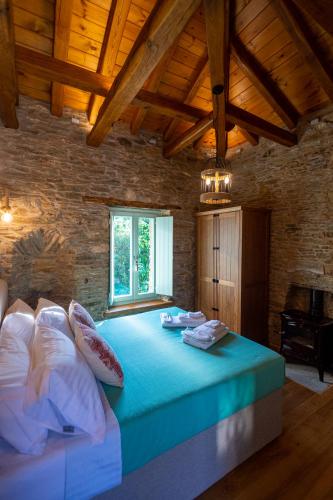 a bedroom with a large bed with blue sheets and pillows at Nostos Country House in Tsagarada