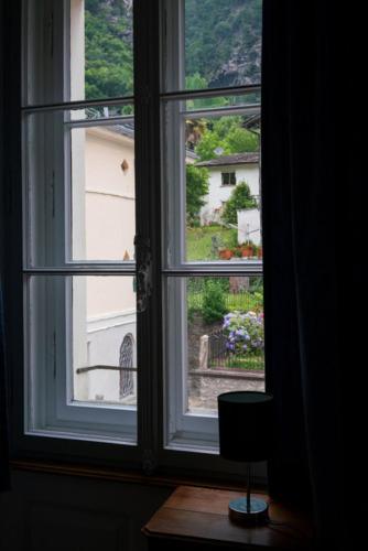an open window with a view of a garden at Das Pöstli – Ristorante Garni Post in Castasegna