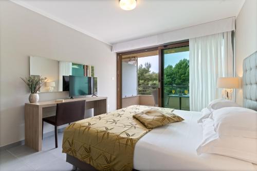 a bedroom with a bed and a desk and a television at The Residence Aparthotel in Podstrana