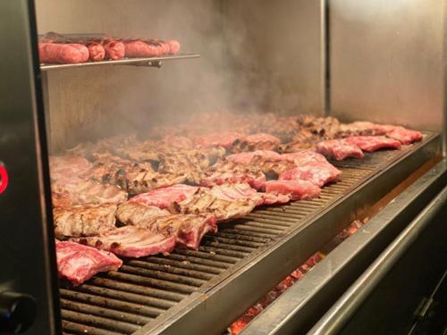 a bunch of meat on a grill in a kitchen at Hotel Alfonso IX in Sarria
