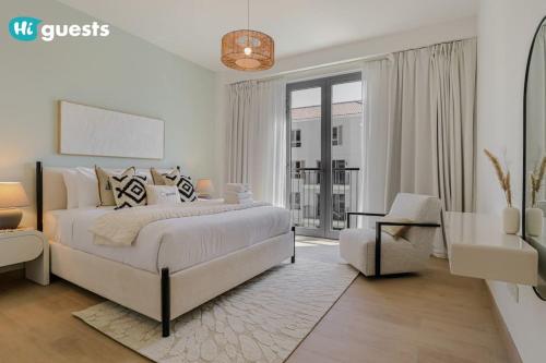 a white bedroom with a large bed and a chair at HiGuests - Beachfront Living Stunning 4 BR with Maid's Room in Dubai