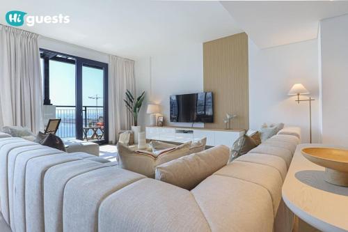 a living room with a couch and a tv at HiGuests - Beachfront Living Stunning 4 BR with Maid's Room in Dubai