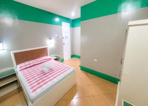 a small bed in a room with green and white walls at Green Meadows Hotel & Restaurant in San Nicolas
