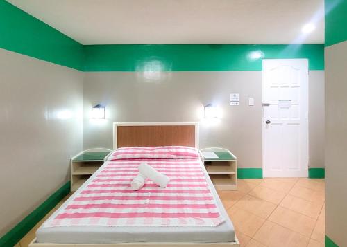 a bedroom with a bed with a pink and white blanket at Green Meadows Hotel & Restaurant in San Nicolas