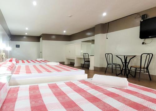 two beds in a room with a tv and a table at Green Meadows Hotel & Restaurant in San Nicolas