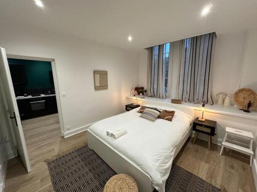 une chambre avec un grand lit blanc et une fenêtre dans l'établissement Santa Fe, appartement neuf proche du centre-ville, à Reims
