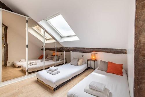 une chambre mansardée avec deux lits et une lucarne dans l'établissement Heart of Saint-Germain only 3 minutes from the Amaizing Luxembourg Gardens, à Paris