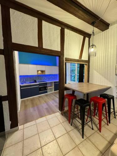 une cuisine avec une table et quelques tabourets rouges dans l'établissement Suite Schwendi - L'Authentique - en Hypercentre, à Colmar