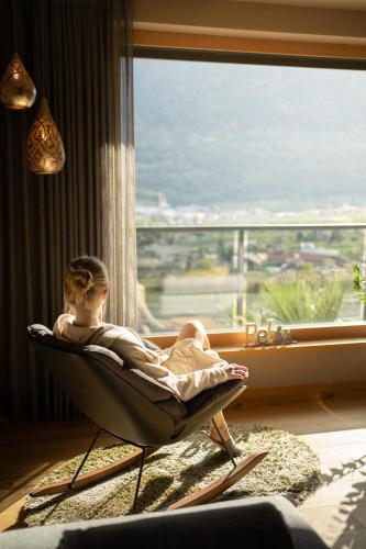 a woman sitting in a chair in front of a window at Nutzhof - Mediterran Flair Hotel in Lagundo