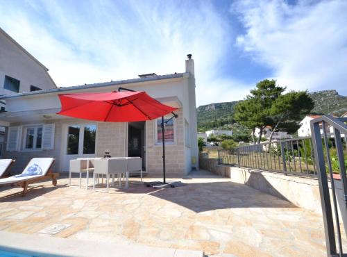 a patio with a red umbrella and a table and chairs at Marvelous Escape Bol Island Villa with Pool in Bol