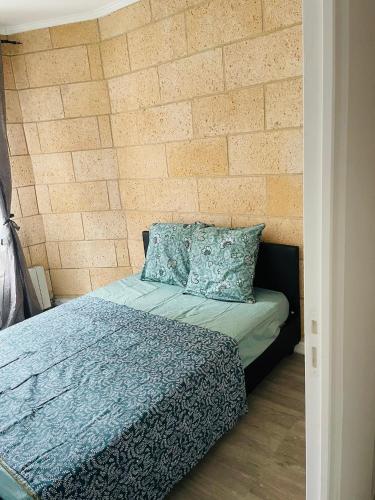 une chambre avec un lit et un mur de briques dans l'établissement Nice Appartement Close Metro, à Saint-Denis