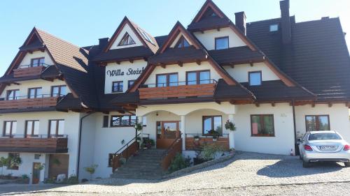 a large white building with a brown roof at Willa Stożek, 50 m od term i wyciągów narciarskich in Białka Tatrzanska