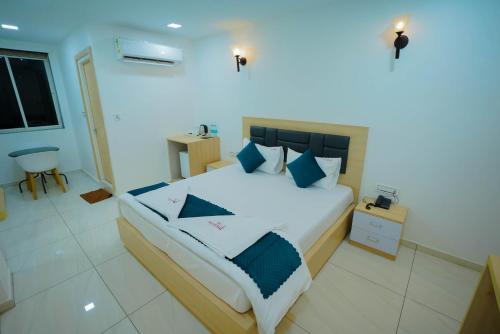 a bedroom with a large white bed with blue pillows at The Balcony Suites I Gachibowli in Hyderabad