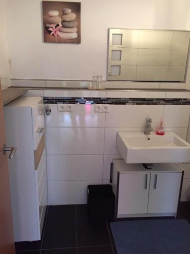 a white bathroom with a sink and a mirror at Apartment Renate Strohhöfer in Hirschaid