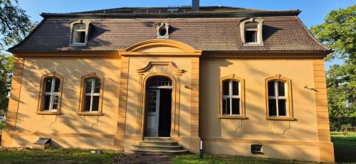 an old yellow house with a brown roof at Schlosshotel Hohenbocka in Hohenbocka