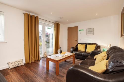 a living room with a leather couch and a table at Bright House with Garden & Patio in Market Town in Inverurie