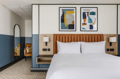 a bedroom with a large bed and paintings on the wall at voco Belfast by IHG in Belfast