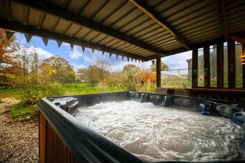 a jacuzzi tub in a pavilion with water at Dragons Barn with Hot Tub in Great Malvern