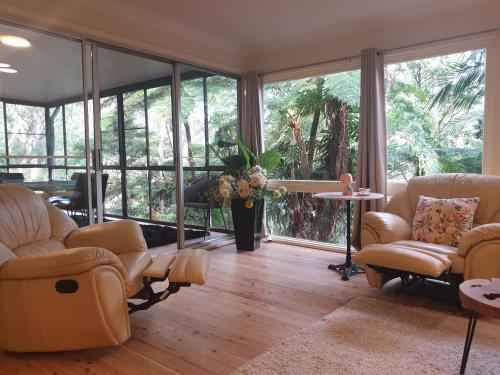 a living room with furniture and large windows at "Forest home,Lake view" in Hornsby