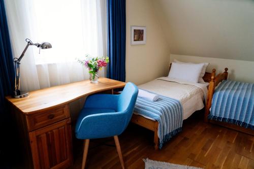 a bedroom with a desk and a bed with a blue chair at Gurudeva Bhavan in Somogyvámos