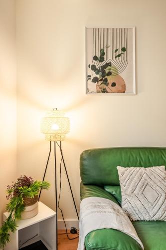- un canapé vert dans le salon avec une lampe dans l'établissement Chaleureux appartement, centre ville, à Narbonne