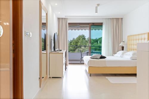 a bedroom with a bed and a television and a balcony at The Residence Aparthotel in Podstrana