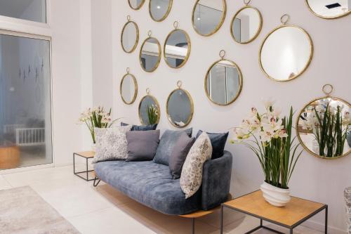 a living room with mirrors on the wall and a blue couch at Abacus Suites in Ayia Napa