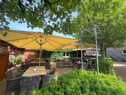 a patio with tables and chairs under a yellow umbrella at Hotel Hilker in Bersenbrück
