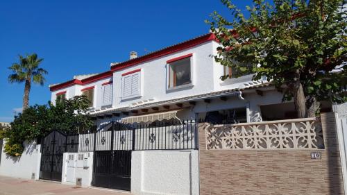 una casa blanca con una valla y un árbol en Casa Naranja, en Los Alcázares