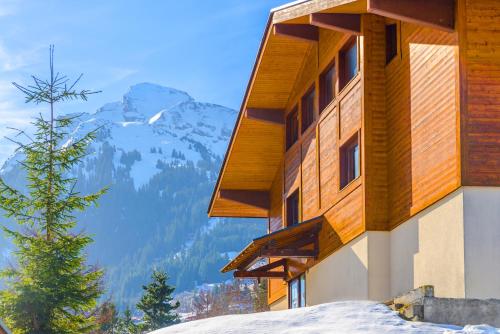 a building in the snow with mountains in the background at Résidence Azureva La Clusaz les Aravis in La Clusaz