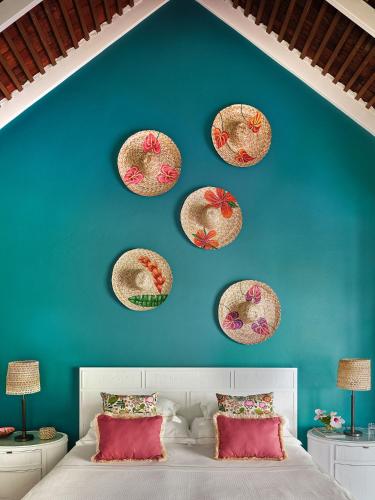 a bedroom with a blue wall with four hats on the wall at East Winds St. Lucia- All Inclusive in Gros Islet