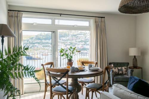 a dining room with a table and chairs and a large window at Harbour View in Dartmouth