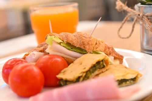 a sandwich on a plate with tomatoes and a glass of orange juice at Best Western Hotel Green City in Parma
