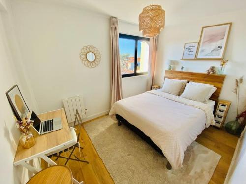 une chambre avec un lit et un bureau avec un ordinateur portable dans l'établissement Appart lumineux 2 chambres - quartier calme au pied du métro, à Toulouse