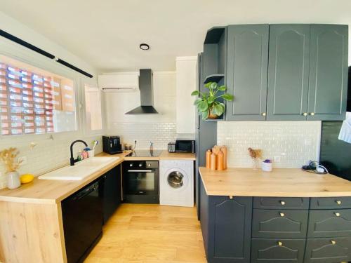 La cuisine est équipée de placards bleus, d'un évier et d'un lave-vaisselle. dans l'établissement Appart lumineux 2 chambres - quartier calme au pied du métro, à Toulouse